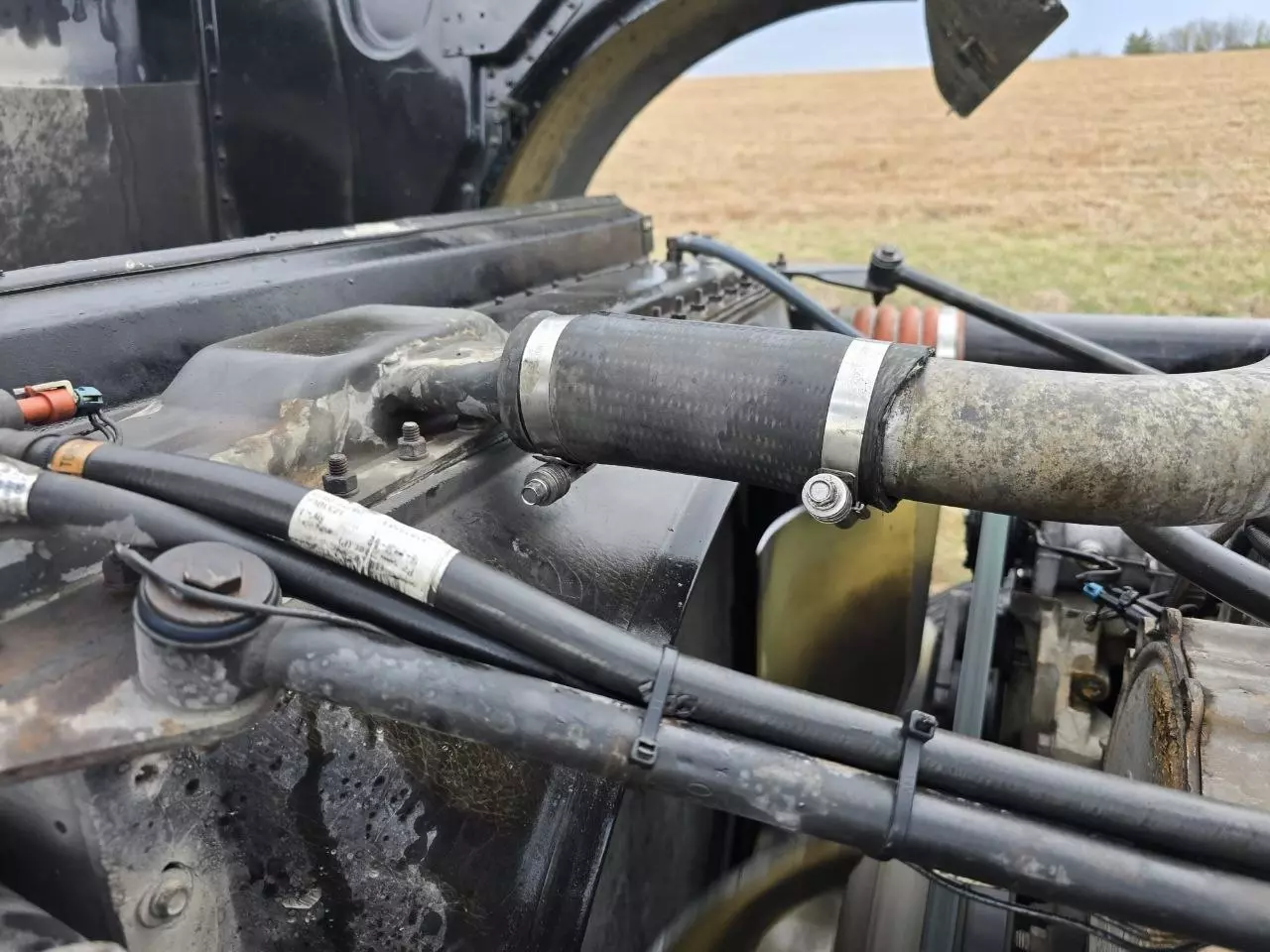 New radiator hose clamped and installed on a semi truck engine during a roadside repair