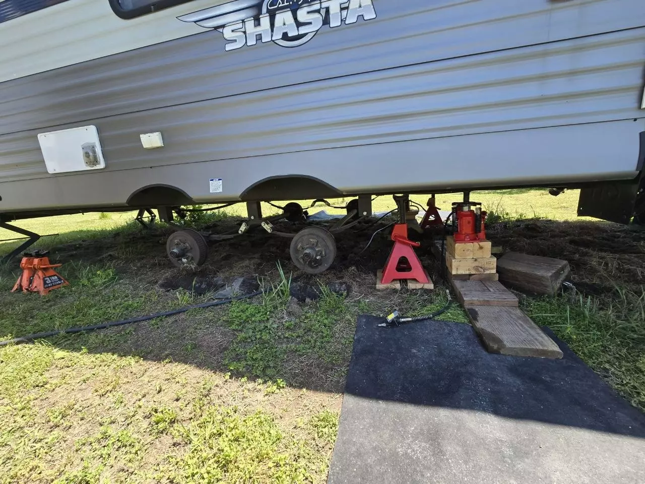 Camper trailer raised on jack stands for tire and axle service