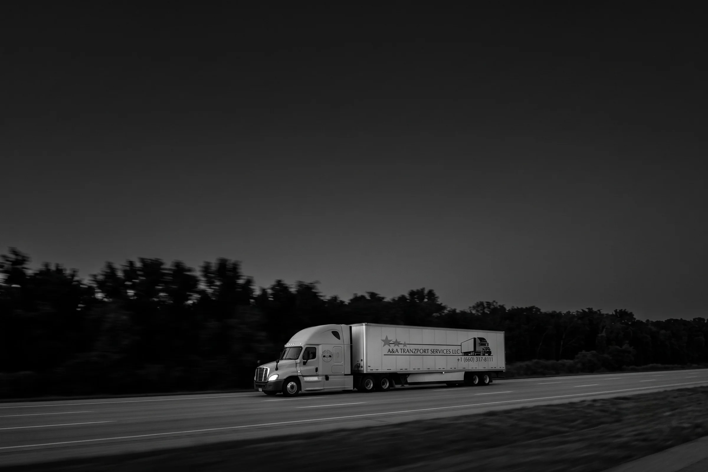 A&A Tranzport semi truck driving on the highway at dusk in black and white
